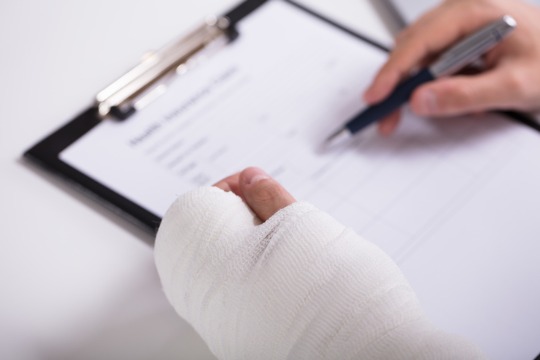 person-with-fractured-hand-filling-health-insurance-form 500x360